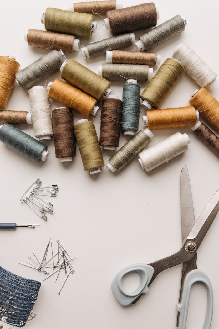 Various sewing threads, pins, and scissors arranged flatly. Ideal for crafting and DIY themes.